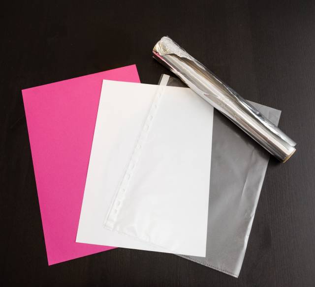 The required ingredients: aluminum foil, a piece of cardboard (pink color is not required), a sheet protector, and a sheet of white paper.