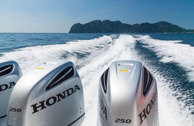 Speed boat engines in front of an island silhouette