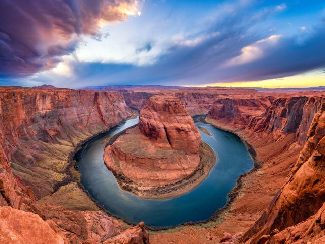 A view of the impressive Horse Shoe Bend at Page with dark clouds at sunset time